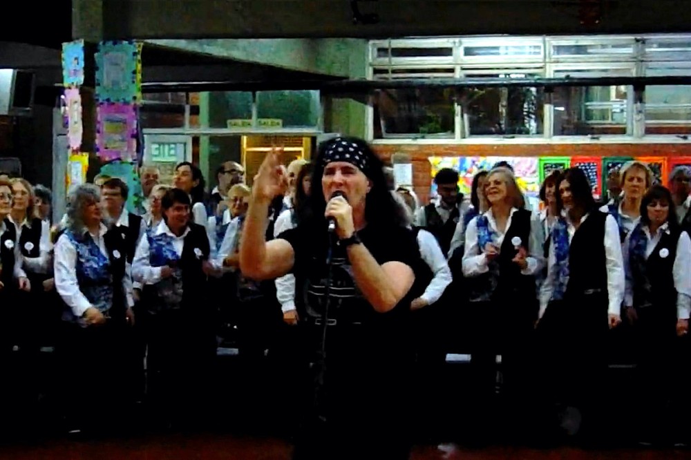 Original AC/DC Singer Dave Evans Performs ‘Highway to Hell’ With Massive Choir